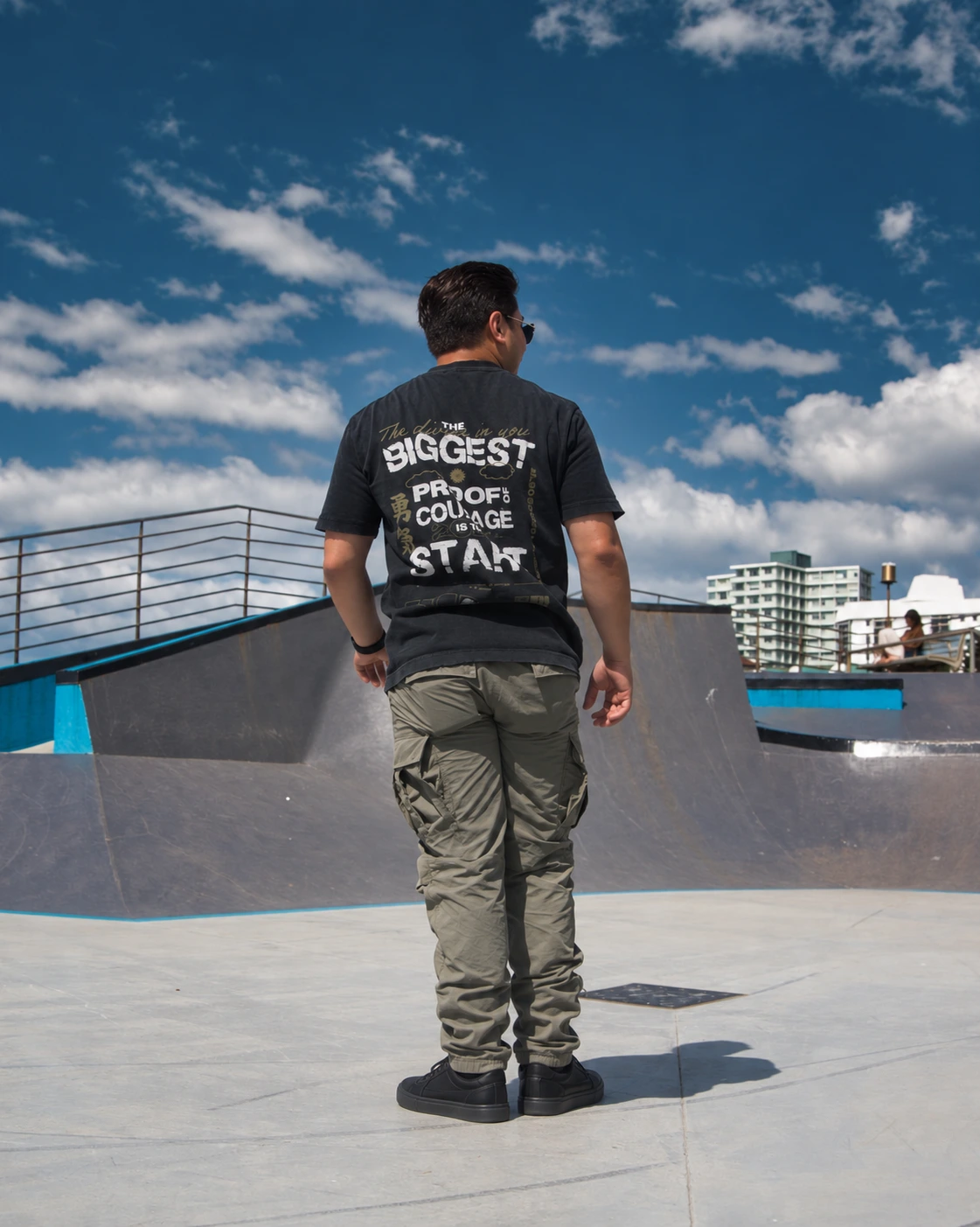 Ricardo con playera BIGGEST, pantalón olivo y tenis negros en un parque de patinaje